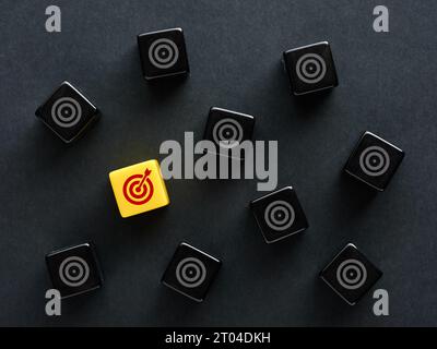 Definizione degli obiettivi e selezione dell'obiettivo più adatto per gli scopi aziendali. Raggiungimento di obiettivi o obiettivi. Simboli obiettivo target su cubi neri. Foto Stock