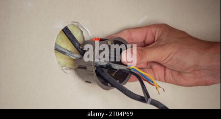 un elettricista inserisce le prese in una parete di cartongesso. Messa a fuoco selettiva. Foto Stock