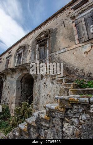 vecchio casale greco abbandonato in cattivo stato di riparazione, con gradini in rovina in vendita per l'acquisto e la ristrutturazione. Foto Stock