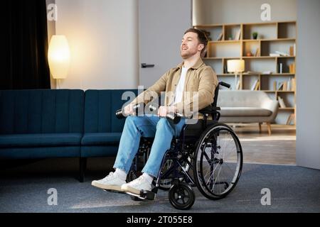 Riabilitazione fisica per disabili. Ragazzo felice in sedia a rotelle fare esercizi con manubri a casa. Giovane uomo allegro e alterato che lavora fuori w Foto Stock