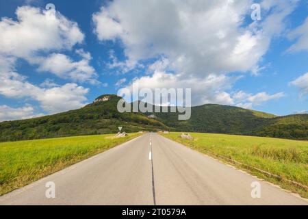 Paesaggio estivo con una strada che sale fino alle colline. Foto Stock