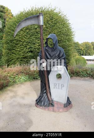 Una personificazione della morte sotto forma di uno scheletro oscurato che brandisce una grande falce, il Grim Reaper, scultura ad Alnwick Gardens, Northumberland. Foto Stock