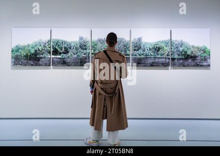 Londra, Regno Unito. 4 ottobre 2023. Un visitatore guarda la "Salt Island" di Monica de Miranda (2022), una serie di 5 immagini che raffigurano un paesaggio verdeggiante. "RE/SISTERS: A Lens on Gender and Ecology" è una nuova mostra alla Barbican Art Gallery che riunisce il lavoro di quasi 50 artisti, analizzando il rapporto tra genere ed ecologia attraverso film, fotografia e installazione. La mostra si svolge fino al 14 gennaio 2024. Crediti: Imageplotter/Alamy Live News Foto Stock