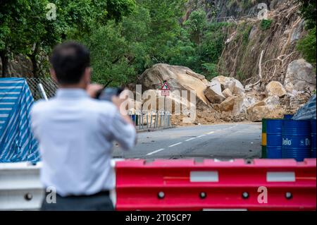 Hong Kong. 4 ottobre 2023. Un uomo cattura immagini di Yiu Hing Road chiusa a causa di una frana dall'inizio di settembre. Quasi un mese dopo che le forti piogge hanno causato una frana nei pressi della tenuta Yiu Tung a Shau Kei Wan, il governo di Hong Kong ha detto che sarebbero passati diversi mesi prima che la strada potesse essere aperta. Sono stati necessari ulteriori interventi per bloccare i detriti sciolti e stabilizzare i grandi massi ancora pendenti dalla pendenza. Con un altro tifone che si avvicina a Hong Kong, alcuni temono che in quest'area potrebbero verificarsi ulteriori danni. Credito: SOPA Images Limited/Alamy Live News Foto Stock