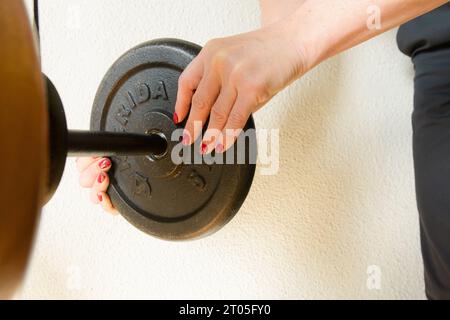 primo piano dettaglio di mani femminili caucasiche che tengono il manichino e lo collocano sulla macchina di allenamento, concetto di stile di vita sano, spazio copia Foto Stock