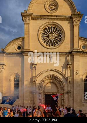 il fumo riempie l'aria dai riflessi rossi mentre una festa di nozze celebra il sole della prima sera di fronte alla cattedrale di sibenik Foto Stock