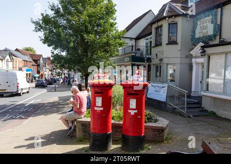 Lyndhurst High Street e due cassette postali tradizionali rosse Royal mail, Hampshire, Inghilterra, Regno Unito Foto Stock