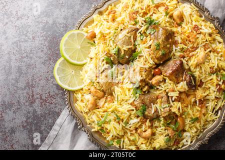 Festive pilaf Kacchi Mutton Biryani con noci, uvetta, primo piano di cipolla fritta sul piatto sul tavolo. Vista superiore orizzontale dall'alto Foto Stock