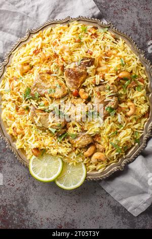 Il tradizionale kacchi biriyani da sposa bengalese serve con noci, uvetta e cipolla fritta per primo piano sul piatto sul tavolo. Vista dall'alto verticale Foto Stock