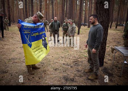 Kupyansk-Lyman, Ucraina. 3 ottobre 2023. Il presidente ucraino Volodymyr Zelenskyy, a destra, è presentato con una bandiera da battaglia dal comandante della 25a brigata aerea separata 'Sicheslava' durante una visita alle linee di fronte nella regione di Charkiv, il 3 ottobre 2023 a Kupyansk-Lyman, Ucraina. Credito: Ucraina Presidenza/Ufficio stampa presidenziale ucraino/Alamy Live News Foto Stock