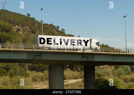 Un veicolo sta attraversando il ponte, con l'iscrizione sul rimorchio - consegna. Concetto di logistica. Foto Stock