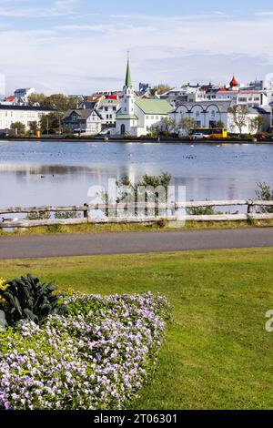 Splendido paesaggio; lago Tjornin Reykjavik Islanda. Un lago nel centro della città di Reykjavik con fiori e cielo blu; Islanda Europa. Foto Stock