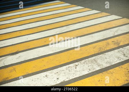 Attraversamento pedonale sulla strada. Contrassegni pedoni. Striscia gialla e bianca sull'asfalto. Contrassegni per il trasporto. Foto Stock