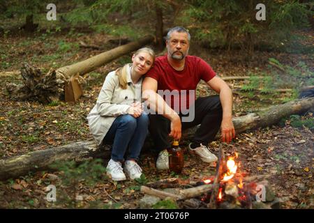 Coppia di viaggiatori che si accampa sul fuoco nella foresta dopo una dura giornata. Concetto di trekking, avventura e vacanza stagionale. Foto Stock