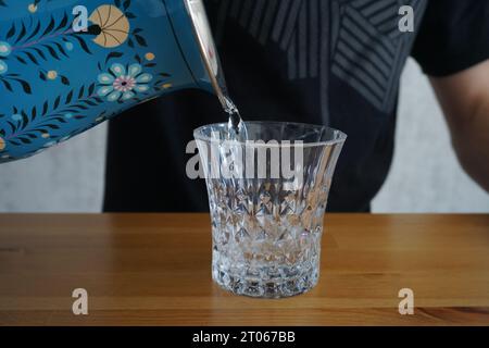 versare l'acqua da una caraffa in un bicchiere. versare l'acqua da una caraffa in un bicchiere. versare a mano l'acqua da una caraffa in un bicchiere. Foto Stock