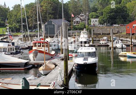 Una varietà di barche attraccate nel porto con una casetta per barche sullo sfondo, Camden, Maine Foto Stock