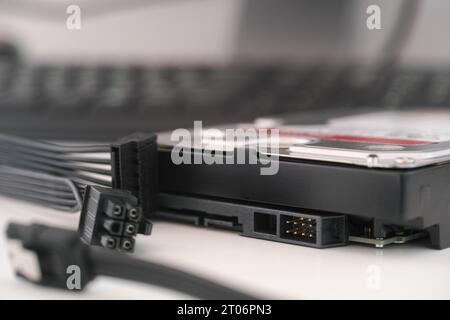 Un'unità disco rigido ad alta capacità nuova di zecca con SATA e cavi di alimentazione nelle vicinanze. Primo piano. Foto Stock