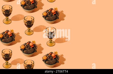 Fantasia autunnale con foglie cadute, frutti di bosco, zucche, pineconi e bicchieri di vino rosso su sfondo arancione pastello. Minima idea della natura Foto Stock