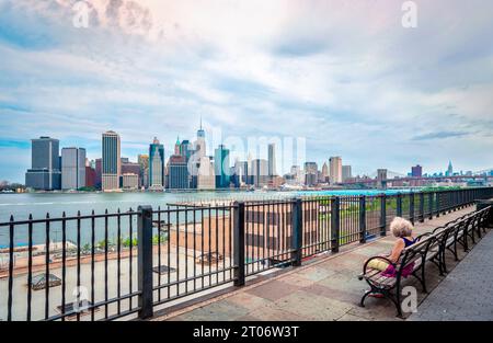 Una donna solitaria non identificata gode della vista dello skyline di Lower Manhattan dalla Brooklyn Heights Promenade. NYC, USA. Foto Stock