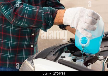 versare l'antigelo. il conducente versa il liquido nel serbatoio del liquido lavavetro. liquido lavavetri. detergente per vetri. uomo che versa il tergicristallo nell'auto. il conducente versa un Foto Stock