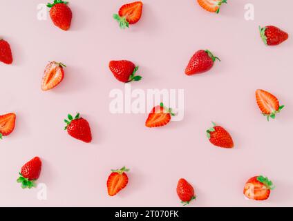 Fantasia di frutta alla moda fatta di fragole fresche e sane su sfondo rosa pastello chiaro. Natura creativa composizione minimale con motivo alle fragole. Foto Stock