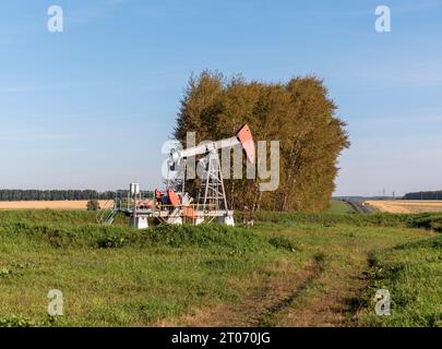 Pozzo di petrolio e gas in giacimento petrolifero, sagomato contro il cielo blu. Foto Stock