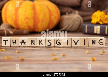 Testo del Ringraziamento su cubi di legno con lettere scritte a mano, foglie autunnali, zucca e Sacra Bibbia. Primo piano. Gratitudine cristiana e lode a Dio. Foto Stock