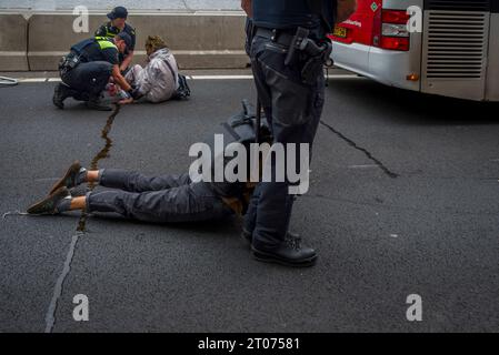 L'Aia, Olanda meridionale, Paesi Bassi. 4 ottobre 2023. Mentre viene arrestato, un attivista per il clima di Extinction Rebellion viene trascinato da un agente di polizia olandese su un veicolo di detenzione. Un'altra attivista, che ha super incollato la mano alla superficie dell'autostrada A12, è stata rimossa da un agente di polizia olandese. Gli attivisti della ribellione di estinzione bloccano l'autostrada A12 a l'Aia, nei Paesi Bassi. (Immagine di credito: © James Petermeier/ZUMA Press Wire) SOLO USO EDITORIALE! Non per USO commerciale! Foto Stock