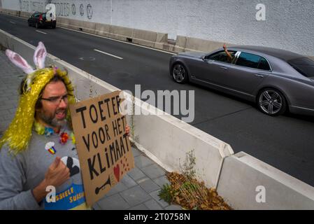 L'Aia, Olanda meridionale, Paesi Bassi. 4 ottobre 2023. Un attivista entusiasta tiene un cartello in olandese con la scritta ''Honk for the Climate'' (tradotto). Un autista dà all'attivista il dito medio. Gli attivisti della ribellione di estinzione bloccano l'autostrada A12 a l'Aia, nei Paesi Bassi. (Immagine di credito: © James Petermeier/ZUMA Press Wire) SOLO USO EDITORIALE! Non per USO commerciale! Foto Stock