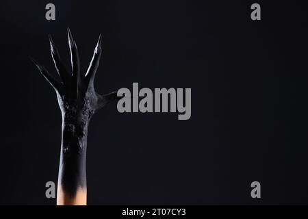 Mano di strega con artigli su sfondo nero. Festa di Halloween Foto Stock