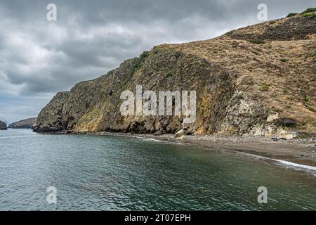 Santa Cruz Island, CA, USA - 14 settembre 2023: Foto pomeridiana della grande scogliera e della montagna a est dello Scorpion Anchorage. Piccolo surf sull'oceano verdeggiante. Foto Stock