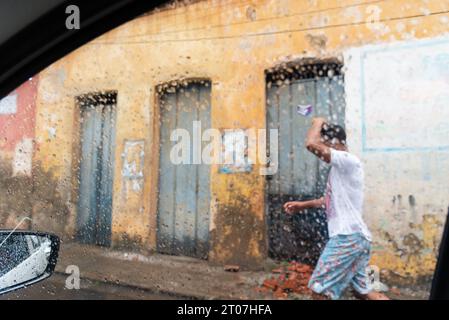 Valenca, Bahia, Brasile - 9 gennaio 2023: Si vedono persone camminare per strada in una giornata di pioggia intensa nella città di Valenca, Bahia. Foto Stock