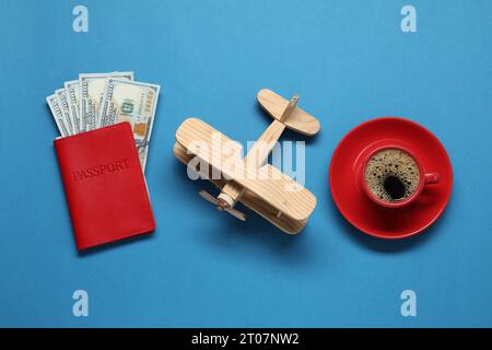 Composizione piatta con passaporto, modello di aereo in legno e dollari su tavolo blu. Viaggio d'affari Foto Stock