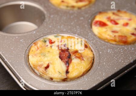 Pancetta appena sfornata e muffin all'uovo con formaggio in stagno, primo piano Foto Stock