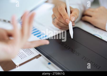 La mano donna tiene lo stilo e inserisce una firma elettronica contratto su tablet Foto Stock