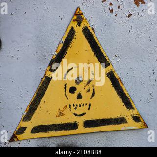 cartello giallo di avvertimento pericolo con cranio sulla cabina del trasformatore Foto Stock