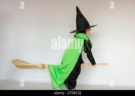 Bambina giocosa vestita come una strega seduta su una scopa, agitando la  mano. Il colore dei calzini che si abbina al colore del divano che sta in  piedi Foto stock - Alamy