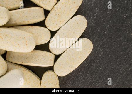 Diverse pillole mediche su pietra di ardesia, macro, vista dall'alto. Foto Stock