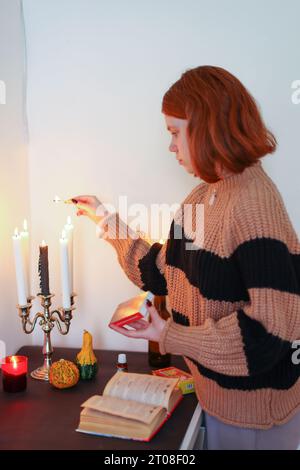 la ragazza accende le candele sul tavolo del predetto della fortuna Foto Stock