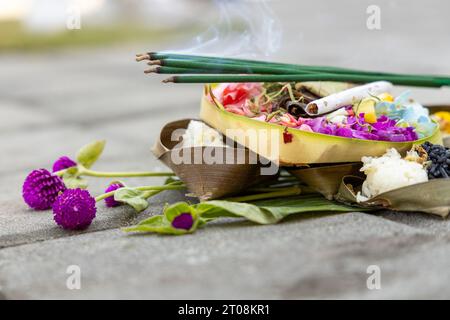 Un'offerta balinese o banten con incenso bruciato visibile Foto Stock