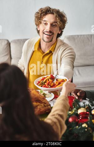 jolly man, circondato dalla sua famiglia, a pranzo festivo, dove si può gustare e condividere cibo festivo, Natale Foto Stock