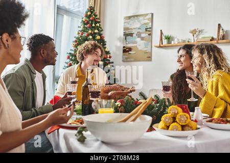 Grande famiglia multiculturale che si diverte a festeggiare il Natale e a godersi un pranzo festivo Foto Stock