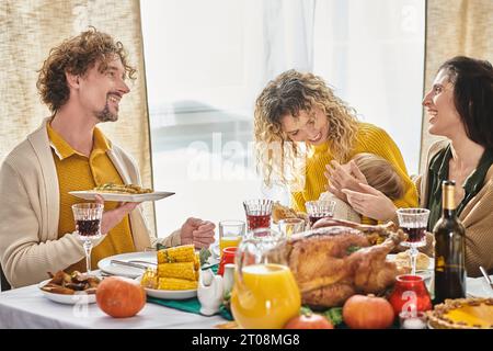 Felice famiglia multirazziale che si gode una deliziosa cena mentre si riunisce il giorno del Ringraziamento con tacchino arrosto Foto Stock