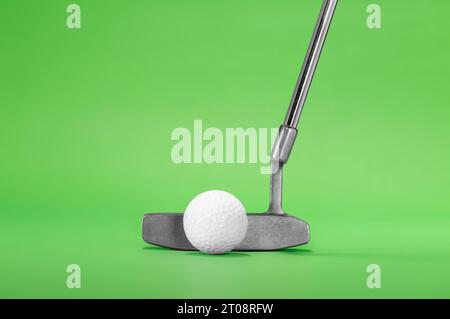 Golf Putter con palla da golf isolata su uno sfondo verde Foto Stock