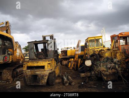 Rottamare il bulldozer e il macchinario in discarica sotto un cielo spettacolare. Attrezzature da costruzione in condizioni inutilizzabili e materiali metallici per pezzi di ricambio o. Foto Stock