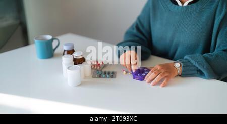 Donne che organizzano il suo farmaco in un dispenser di pillole. donna che prende pillole dalla scatola. Sanità e concetto con i farmaci. Medicinali sul tavolo Foto Stock