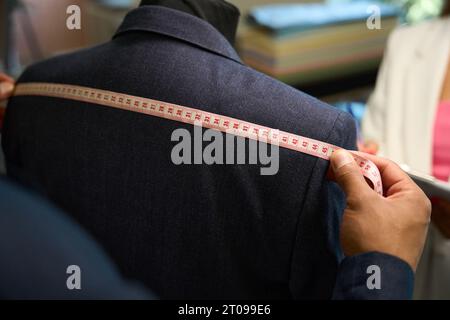 Master Tailor che effettua misurazioni su misura degli indumenti sul manichino Foto Stock