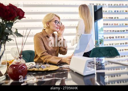 Bella donna che prova gli occhiali in un salone di ottica Foto Stock