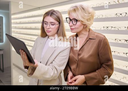 Due donne con gli occhiali stanno guardando qualcosa sul tavolo Foto Stock