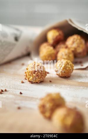 Dolci pananellette in coni da giornale collocati su un tavolo di legno contro una parete bianca sfocata Foto Stock